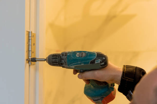 istock Handyman using a drill to installing lock in door in a house 1395562491