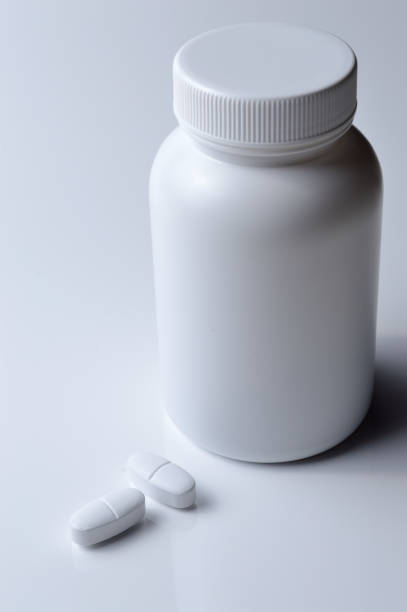 istock white plastic medicine jar and two white pills. light background. 1395563547