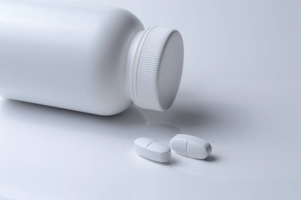 istock white plastic medicine jar and two white pills. light background. 1395563550
