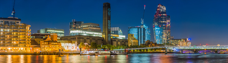 Night time panoramic view across the River Thames and the Millennium Bridge to the landmarks of the South Bank in the heart of London, UK.