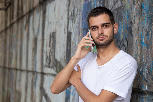 portrait of young man with mobile phone on the street