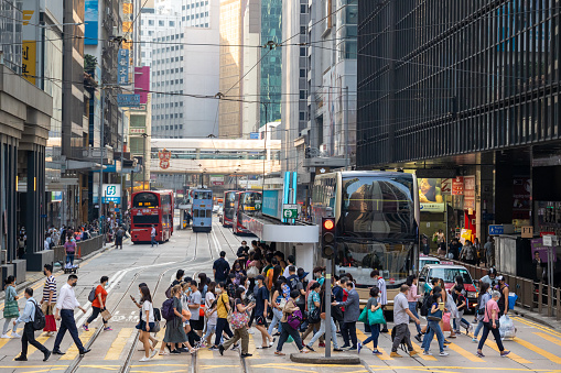 Hong Kong - April 14, 2022 : Pedestrians walk past the Des Voeux Road Central in Central, Hong Kong. Des Voeux Road Central was named after the 10th Governor of Hong Kong, Sir William Des Vœux.