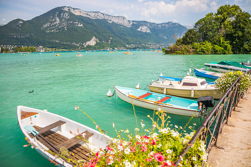 Boats moored to the flowered banks of Lake Annecy in the French Alps in France