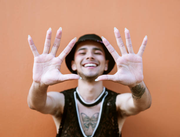 istock Young man with tattoos extending his arms while smiling and showing his long fingernails. Lgbti community and lifestyle. 1395569384