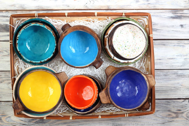 istock Many different bright multicolored ceramic bowls and cups handcrafted on tray on white wooden background. Top view. Background texture. 1395570155