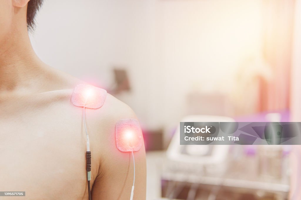 TENS Electrode Pads prepare for treatment on shoulder pain, Selective focus on TENS Electrode Pads prepare for treatment on shoulder pain, Electro stimulation machine in rehab room on the background in hospital, health problem and medical concept. Chronic Illness Stock Photo