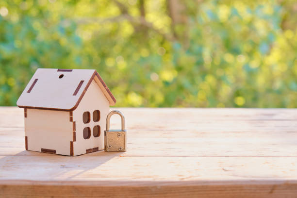 istock Home security concept: Wooden model house and lock on wooden surface. 1395578717
