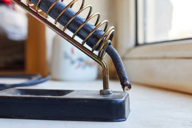 soldering iron in a spiral holder on a stand selective focus with blurred background