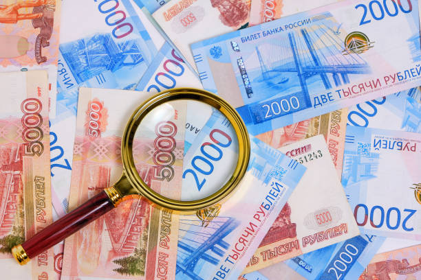 istock Magnifying magnifier against background Russian rubles denominations five and two thousand. 1395580988