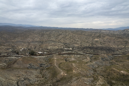 arid landscape of the desert of Tabernas in Almeria (Spain), it is a mountainous landscape, there are several houses, there are bushes and the sky is cloudy
