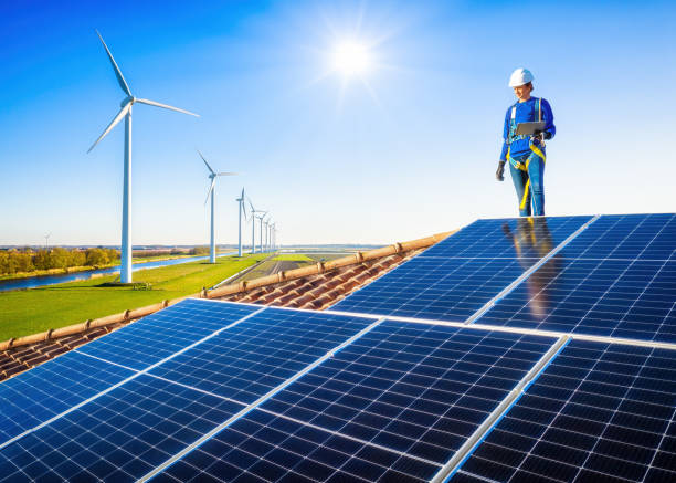 concepto de energía limpia, paneles fotovoltaicos y aerogeneradores con una mujer tecnicista en una azotea - autoconsumo fotografías e imágenes de stock