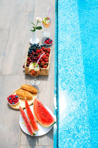 istock Breakfast by the pool which includes non-alcoholic beverages, berries, croissants and watermelon. View above. Vertical photography. 1395585821