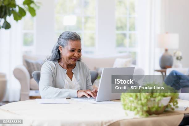 Mother Sits At Her Computer Answering Emails Stock Photo - Download Image Now - Senior Adult, Using Computer, Laptop