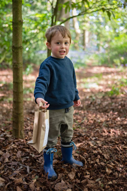 niño de pie en el bosque con bolsa de actividades - glade england autumn forest fotografías e imágenes de stock