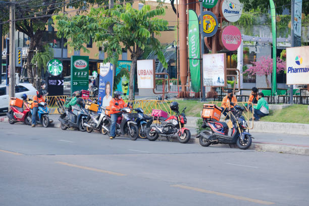 Queued delivery service people with motorcycles in Bangkok. Scene is on Wanghin Road in Ladprao. Men are waiting for calls near The jas and Starbucks as small shopping center