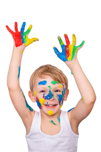 istock A cheerful boy, painted with finger paints, raises his painted hands up on a white background 1395593588