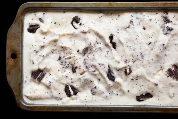 Close-up of homemade cookies and cream ice cream in a metal tin showing the texture of the cookie ice cream.