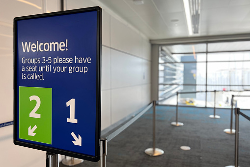 Blue and green sign showing groups 1 and 2 for passengers at the gate prior to departure.