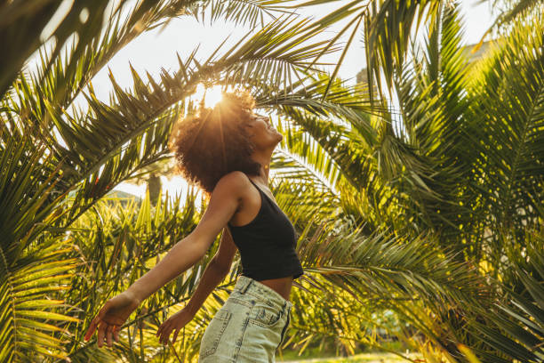 istock Pretty young afro woman among palm trees 1395597158