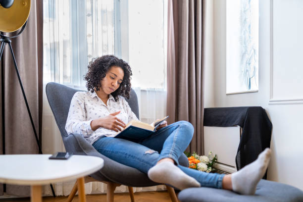 istock Afro woman lounging reading a book 1395597818