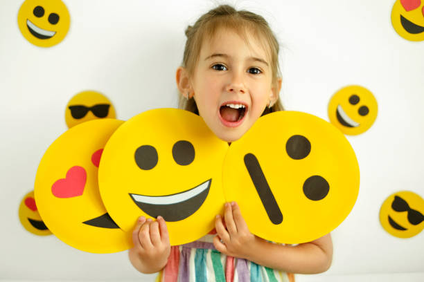 istock Human holds emoticons with different emotions in her hands: a sad, smiling happy smile, a loving smile with hearts instead of eyes.  A joy emotional humorous girl. 1395599521