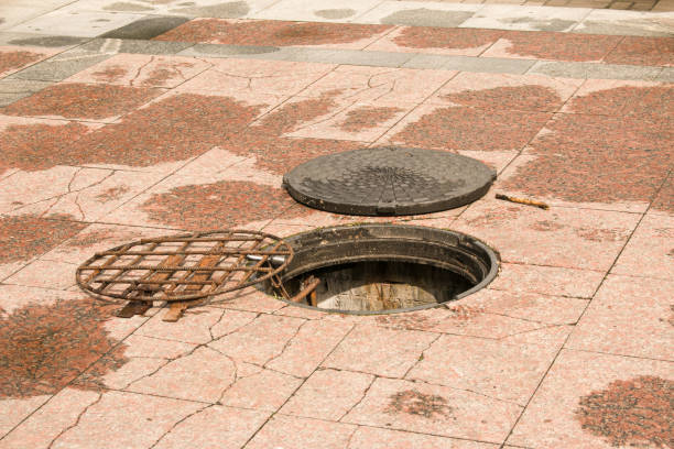 An open manhole on the road. Dangerous open unsecured hatch on the road. Accident with sewer hatch in city. Concept of sewage, repair of underground communications stock photo