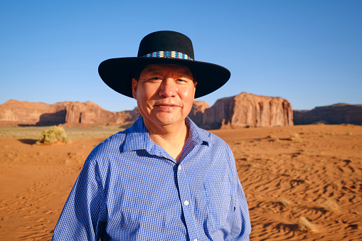 A Native American Navajo man standing in the desert at Monument Valley USA.