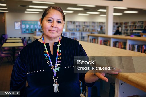 istock High School Teacher in a Library 1395601958