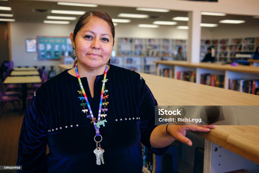 High School Teacher in a Library A portrait of a Native American Navajo high school teacher in a school library. Indigenous Peoples of the Americas Stock Photo