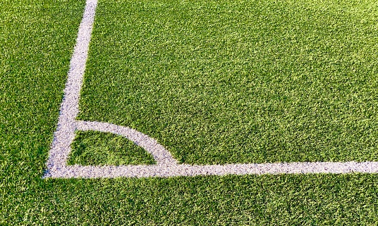 Detail view of the corner in a green football field made of artificial grass