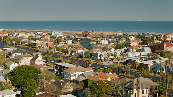 Aerial view of Galveston, Texas on a bright sunny day. The drone flies over historic homes and residential streets in the East End. \n\nAuthorization was obtained from the FAA for this operation in restricted airspace.