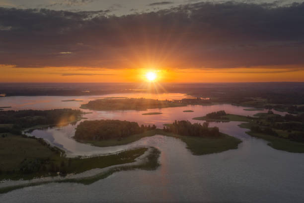 istock Amazing aerial hyperlapse beautiful lakes at sunset, sun rays break through storm clouds in sky illuminate green islands of various shapes. Drone flies over incredible landscape in national park 1395605893