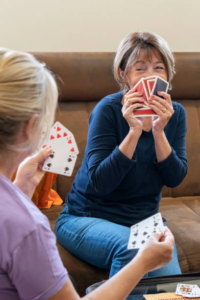 istock Two senior woman enjoying while playing cards at home 1395606618