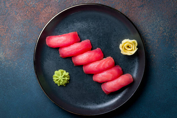 unos pocos atunes de sushi en un plato negro en una hermosa vista azul de la mesa de concreto - nigiri fotografías e imágenes de stock