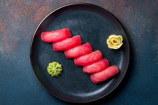 Sushi and sushi roll set (Sake nigiri sushi, notate nigiri sushi, avocado nigiri sushi, Philadelphia rolls, spicy tuna roll, scallop roll). Tuna tataki. Gunkan set. Rice bowl with salmon. Flat lay top-down composition on dark background.