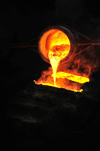 Foundry - molten metal poured from ladle into mould stock photo