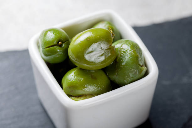 istock Green olives on dark stone plate on white bowl 1395609037