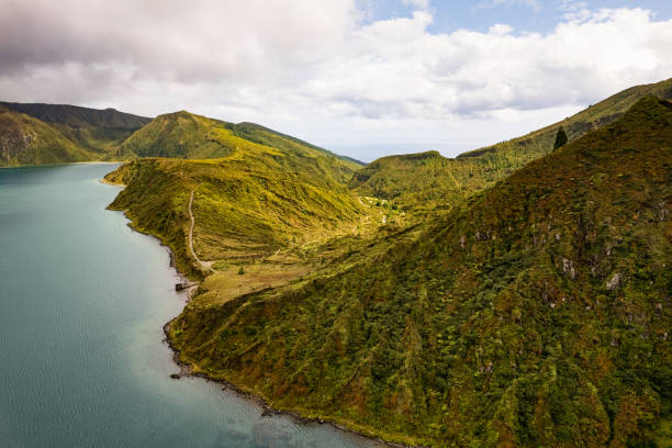istock Green hills and lake under cloudy sky 1395629846