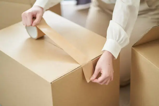 Asian woman sticking gum tape on cardboard