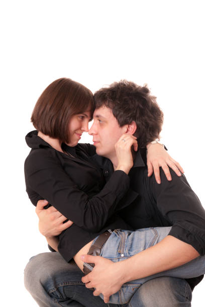 Two young adult men showing affection outdoors, one hugging the other from behind with a joyful expression