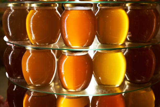 frascos de diferentes variedades de miel en un estante - honeyed fotografías e imágenes de stock