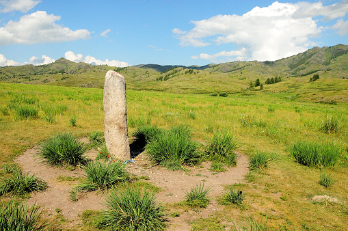 An ancient granite monolith in the center of a picturesque valley surrounded by high mountains. Ah-Tas, Khakassia, Siberia, Russia.