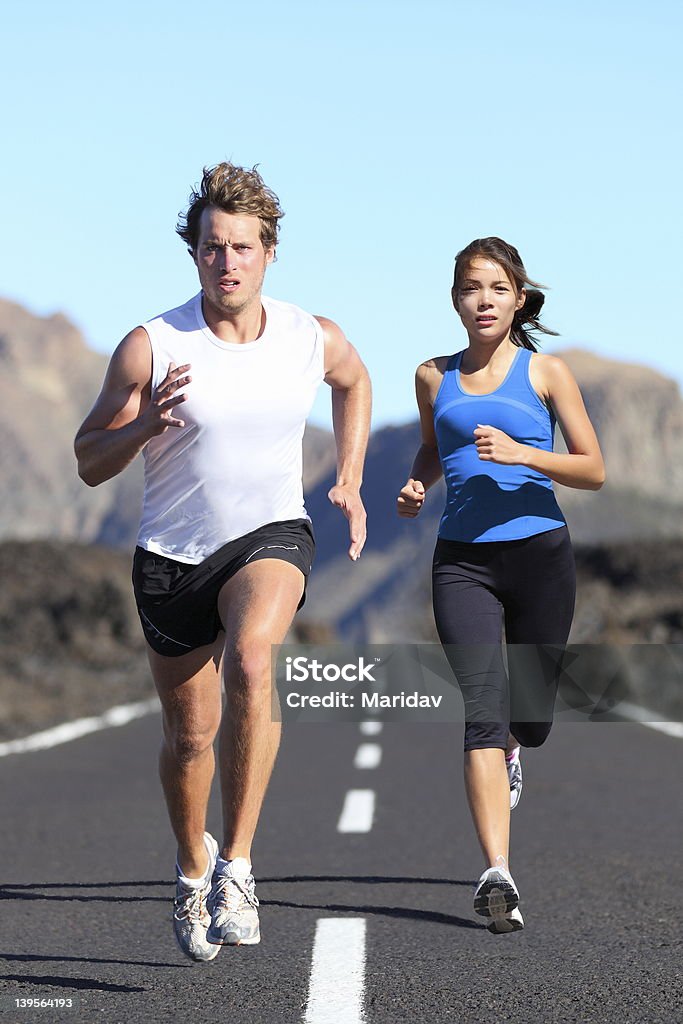 Running couple Running couple. Runners outdoor jogging workout on road beautiful landscape. Fit athletes training, Caucasian man, Asian woman. More: Couple - Relationship Stock Photo