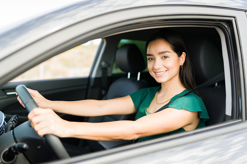 Portrait of a beautiful young woman getting behind the wheel while traveling by car