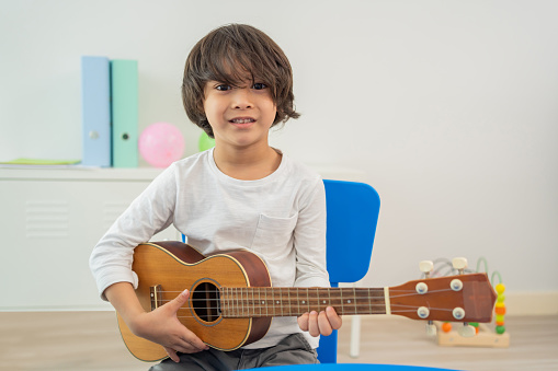 Back to school and summer course. Little children play guitar in kindergarten classroom.