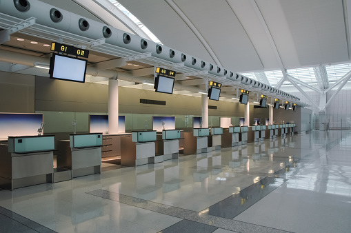 A row of empty check-in counters inside a modern airport.