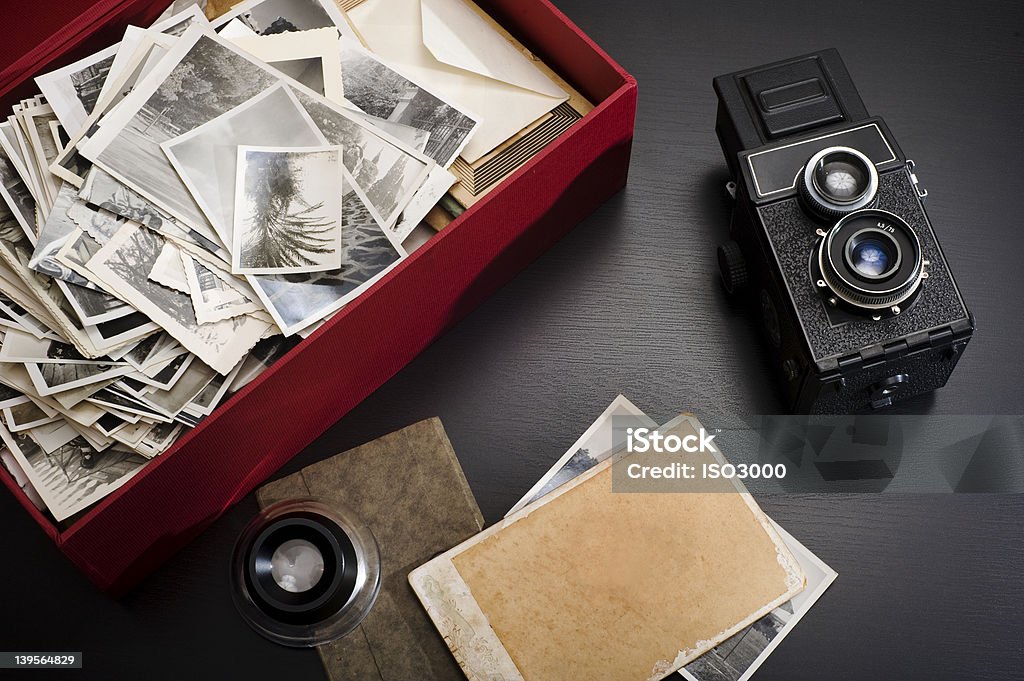 Box with photos A box with family vintage photos on a table with a magnifying glass and a vintage camera next to it Photographic Print Stock Photo