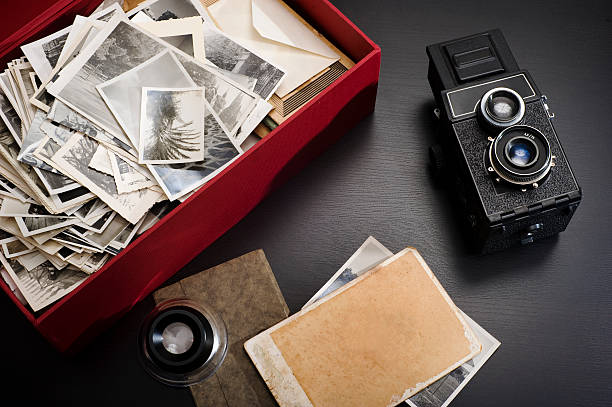 Box with photos A box with family vintage photos on a table with a magnifying glass and a vintage camera next to it nostalgia photos stock pictures, royalty-free photos & images