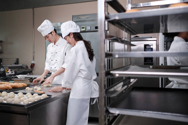 istock Two Asian chefs in uniforms prepare to bake bread and pastry in a kitchen. 1395649245