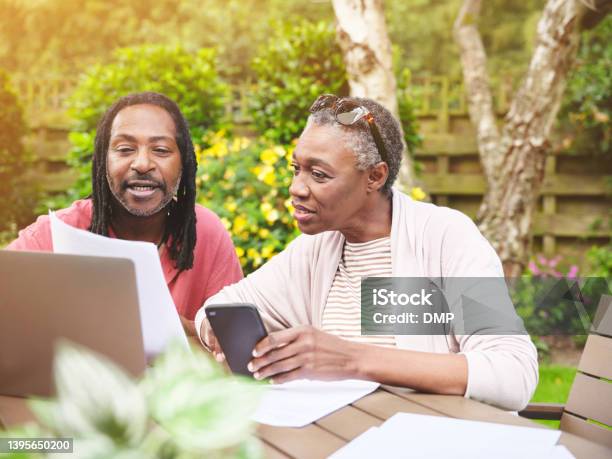 A Senior Couple Using A Laptop And Going Over Paperwork In The Garden At Home Mature Man And Woman Discussing Finance While Browsing Online With A Computer Stock Photo - Download Image Now